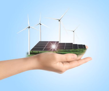 Açık mavi arka planda güneş paneli ve rüzgar türbinleri gösteren bir kadın, yakın plan. Alternatif enerji kaynağı 