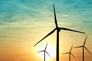 Gün batımında rüzgar türbinlerinin siluetleri. Alternatif enerji kaynağı