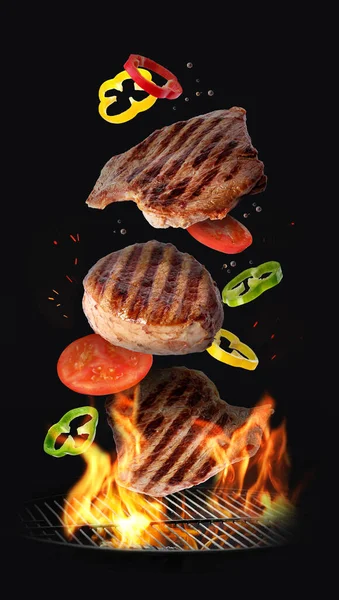 濃い背景に火をつけてバーベキューグリルに落ちるおいしいロースト肉や野菜 — ストック写真