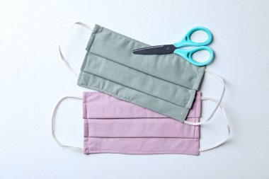 Beyaz arka planda ev yapımı koruyucu maskeler ve makas düz yerde. Dikiş fikri