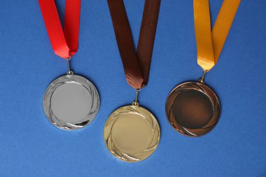 Mavi arka planda altın, gümüş ve bronz madalyalar, düz yatış. Tasarım için boşluk