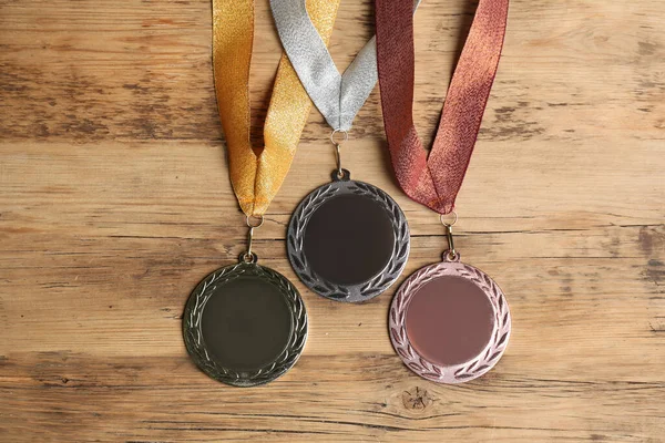 Gold, silver and bronze medals on wooden background, flat lay. Space for design