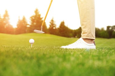 Güneşli bir günde parkta golf oynayan adam.