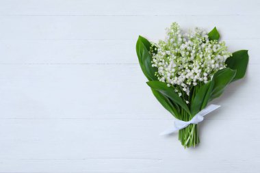 Vadi çiçeklerinin güzel zambakları beyaz ahşap masada, üst manzara. Metin için boşluk