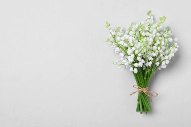 Açık gri arka planda, vadideki çiçeklerin güzel zambakları, üst manzara. Metin için boşluk