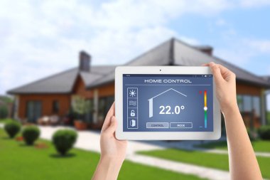 Enerji verimliliği ev kontrol sistemi. Kapalı alan sıcaklığını ayarlamak için tablet kullanan kadın, kapat
