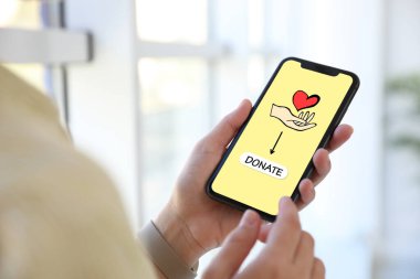 Bağış konsepti. Akıllı telefonlu bir kadın, kapalı bir yerde.