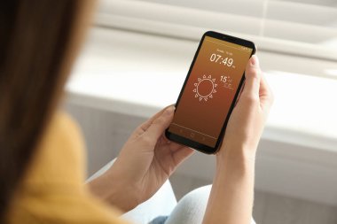 İçerideki akıllı telefondan hava durumu uygulaması kullanan kadın, yakın plan.