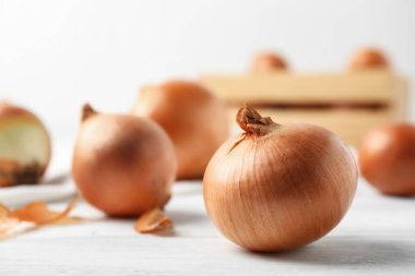 Beyaz ahşap masada olgun sarı soğan soğanları, yakın plan.