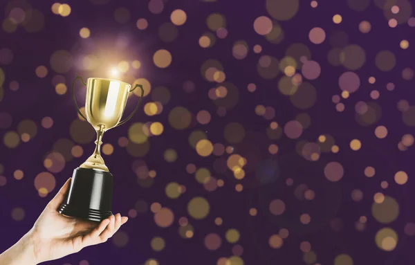 Woman holding gold trophy cup on violet background, closeup. Space for text