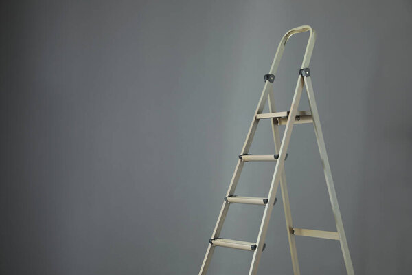 Metal stepladder on grey background. Space for text