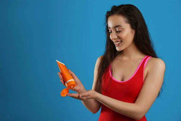 Jovem Aplicando Creme Proteção Solar Fundo Azul Escuro — Fotografia de Stock