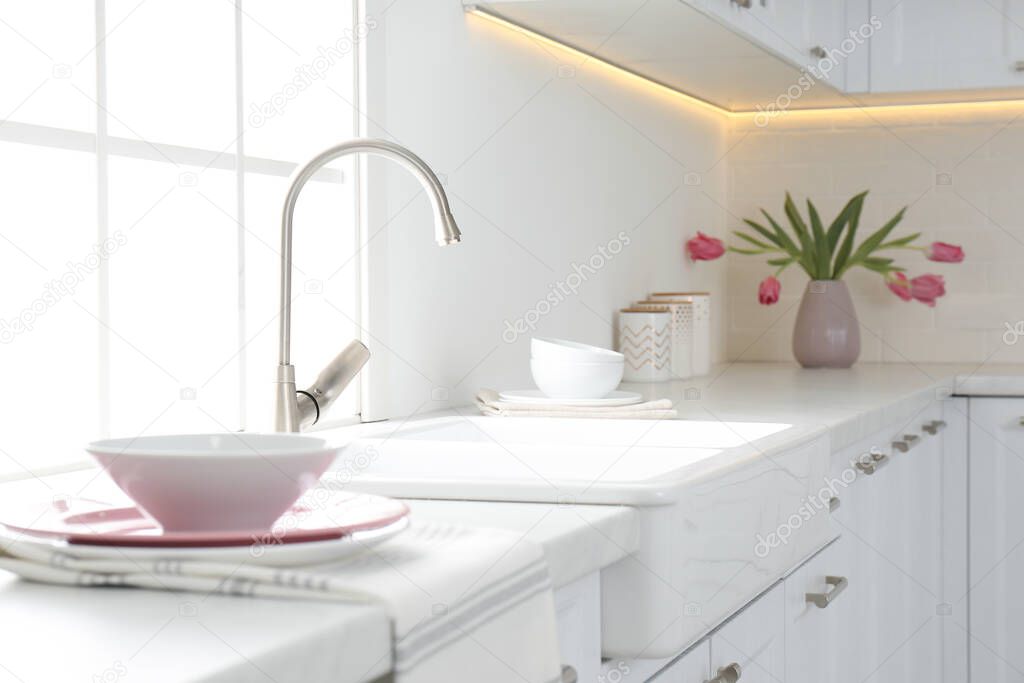 Beautiful ceramic dishware and bouquet on countertop in kitchen