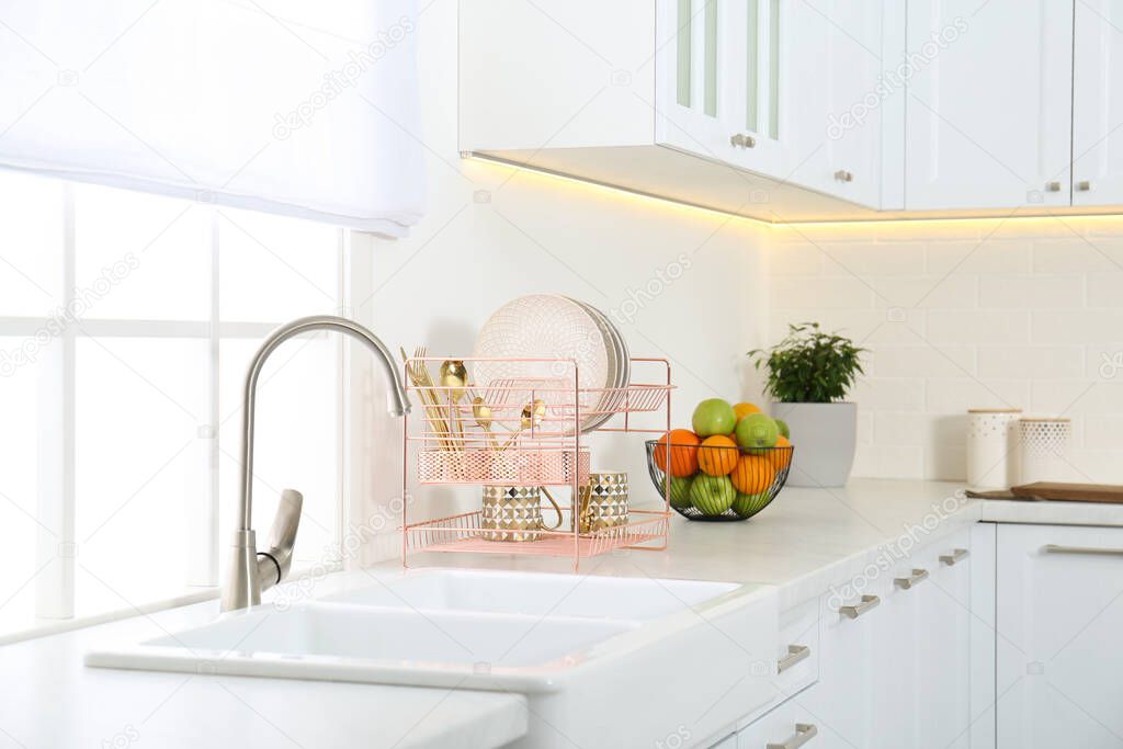 Clean dishes on drying rack in modern kitchen interior