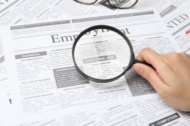Gazetede büyüteçten bakan bir kadın, yakın plan. İş arama konsepti