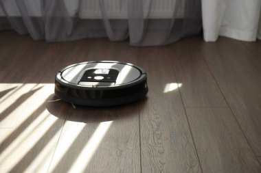 Ahşap zeminde modern robot elektrikli süpürge. Metin için boşluk