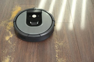 Modern robotik elektrikli süpürge ahşap zeminden dağınık Groats 'u kaldırıyor. Metin için boşluk