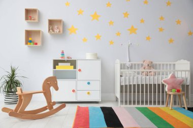 Bebek odasının içinde beşik ve oyuncaklar var.