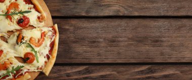 Tahta masadaki sıcak ve lezzetli pizzanın üst görüntüsü, mesaj için yer. Pankart tasarımı 