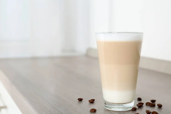 Leckere Latte Macchiato Und Kaffeebohnen Auf Einem Holztisch Drinnen Raum — Stockfoto