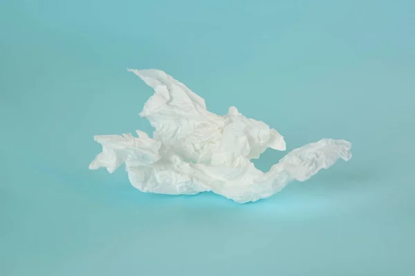 Used paper tissue on light blue background, closeup