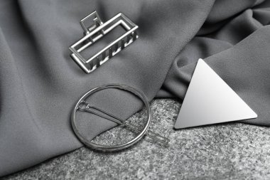 Gri masanın üstünde güzel farklı saç tokaları ve kumaşlar var.