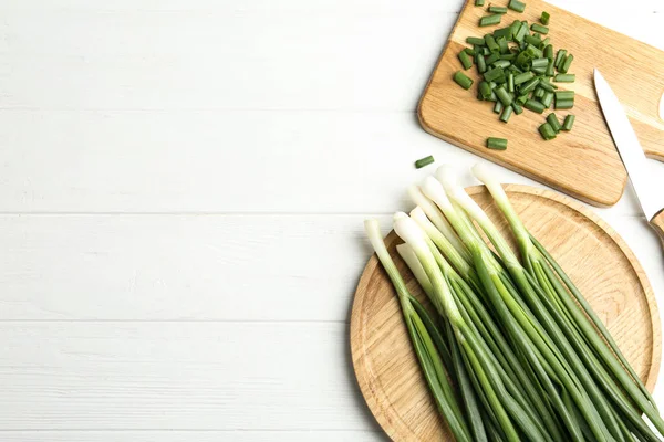 新鮮な緑の春の玉ねぎ ナイフと白い木製のテーブルの上にまな板 フラットレイアウト テキストのスペース — ストック写真