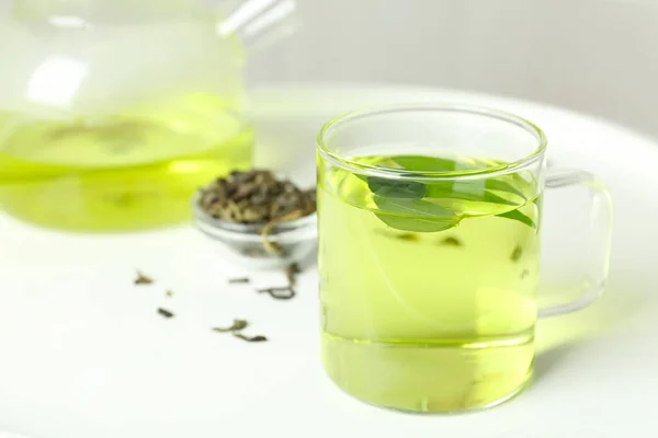 Tasse Aromatischer Grüner Tee Mit Blättern Auf Weißem Tisch — Stockfoto