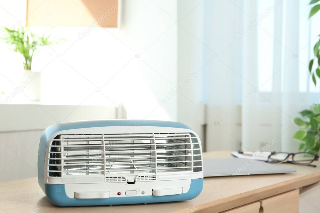 Modern air purifier on wooden table in room