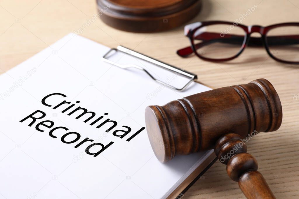 Clipboard with words CRIMINAL RECORD and gavel on wooden table, closeup