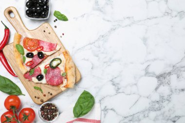Lezzetli pizza parçaları ve beyaz mermer arka planda malzemelerle bezenmiş düz bir kompozisyon. Metin için boşluk