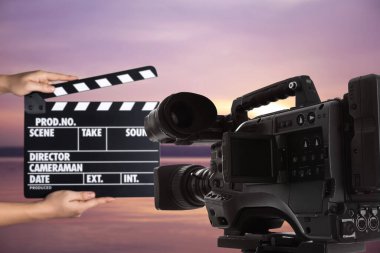 Modern video kamera ve dışarıda el çırpma tahtası olan asistan, yakın çekim. Sinema yapımı 