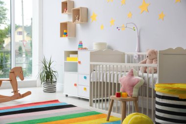 Bebek odasının içinde beşik ve oyuncaklar var.