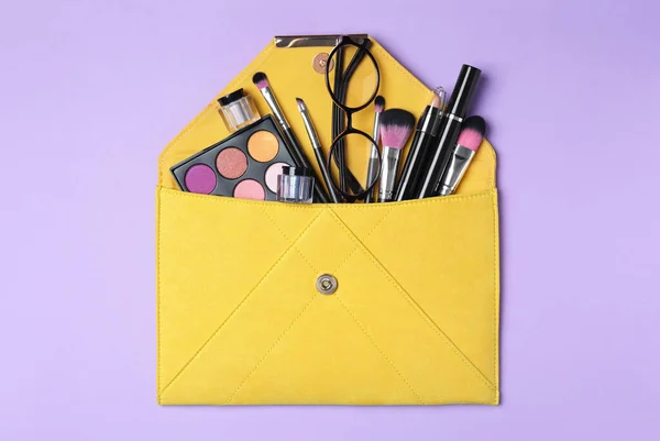 有化妆品和紫罗兰色背景的美容品的化妆品袋 顶视图 — 图库照片
