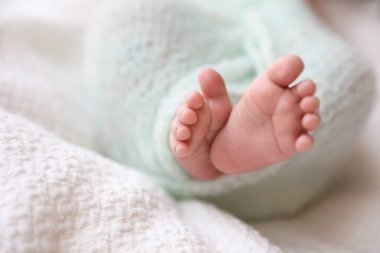 Yeni doğmuş bebek ekose üzerinde yatıyor, bacakları yakın plan. Metin için boşluk