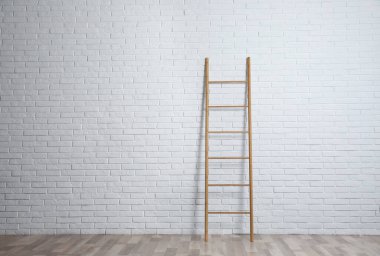 Beyaz tuğla duvarın yanındaki modern tahta merdiven.