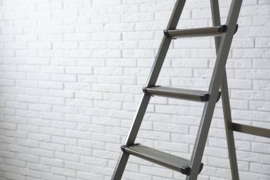 Beyaz tuğla duvarın yanındaki metal merdiven, yakın plan. Metin için boşluk