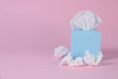 Kağıt mendilli kutu ve pembe arka planda buruşmuş peçeteler, metin için boşluk