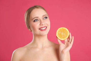 Pembe arka planda turuncu kesilmiş genç bir kadın. Vitamin zengini yiyecekler