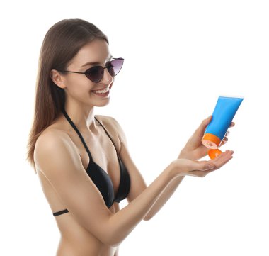 Beyaz arka plana güneş kremi süren genç bir kadın.