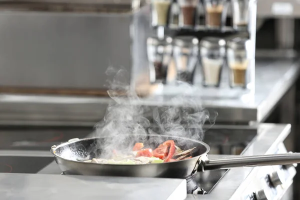 Cooking tasty food on stove in restaurant kitchen