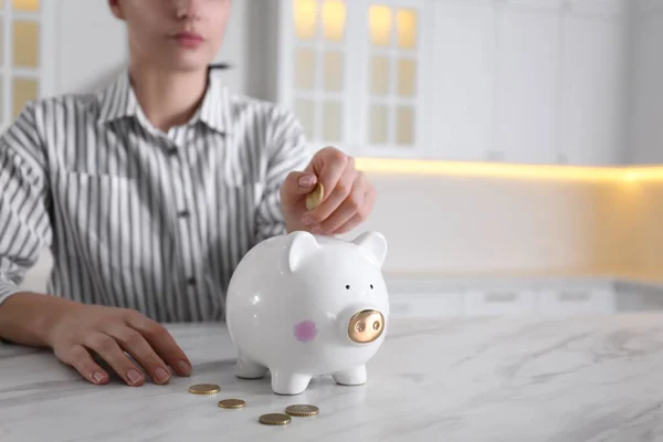 Woman Putting Money Piggy Bank White Marble Table Indoors Closeup — Stock Photo, Image