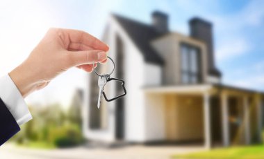 Yeni modern evin yakınında anahtarı olan bir kadın, yakın plan.