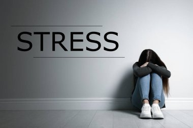 Kelime STRESS ve depresif genç kız içeride oturuyor.