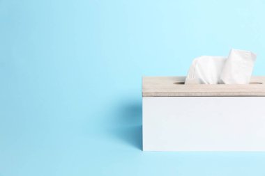 Açık mavi arka planda kağıt mendilli tutucu. Metin için boşluk