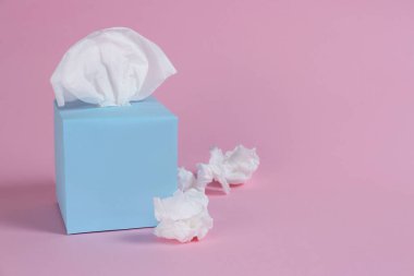 Kağıt mendilli kutu ve pembe arka planda buruşmuş peçeteler, metin için boşluk