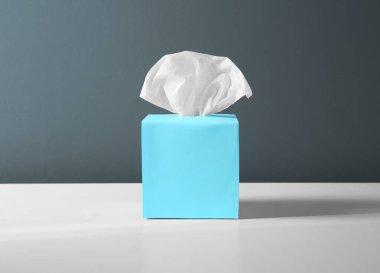 Beyaz masanın üzerinde kağıt mendiller olan kutu.