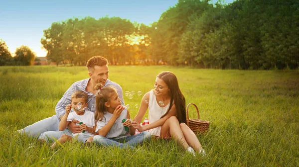 Happy Family Having Picnic Blowing Soap Bubbles Park Sunset — Stock Photo, Image
