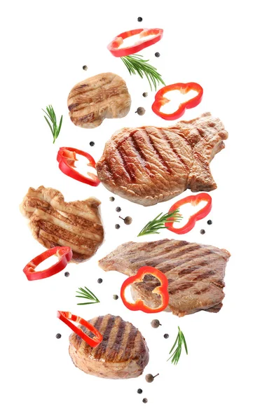 Delicious grilled meat and other ingredients falling on white background