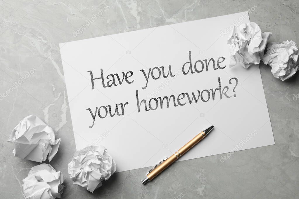 Paper sheet with phrase HAVE YOU DONE YOUR HOMEWORK? on grey marble table, flat lay 